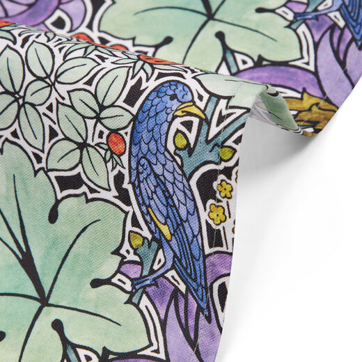 Detail of tea towel with a pattern of foliage, birds and strawberries.